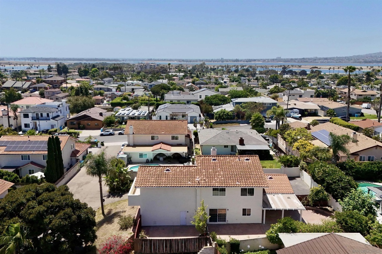 Aerial view over the rooftop of 1839 Galveston Street looking west, rows of rooftops below and the water of Mission Bay stretching across the horizon